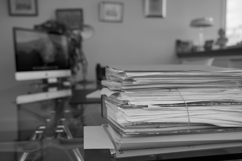 Piles de dossiers sur le bureau du cabinet, en noir et blanc